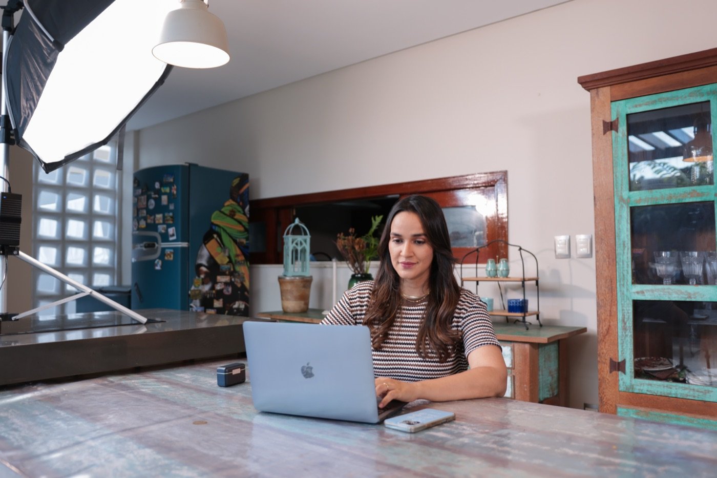 Izabel trabalhando no notebook em um setup com boa iluminação e ambiente organizado